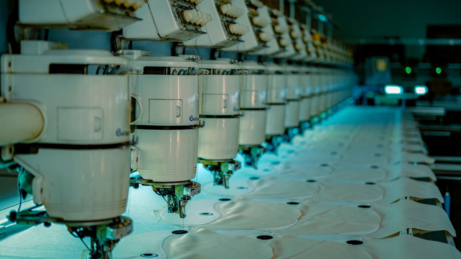 Rows of sewing machines with grey polo shirts in production