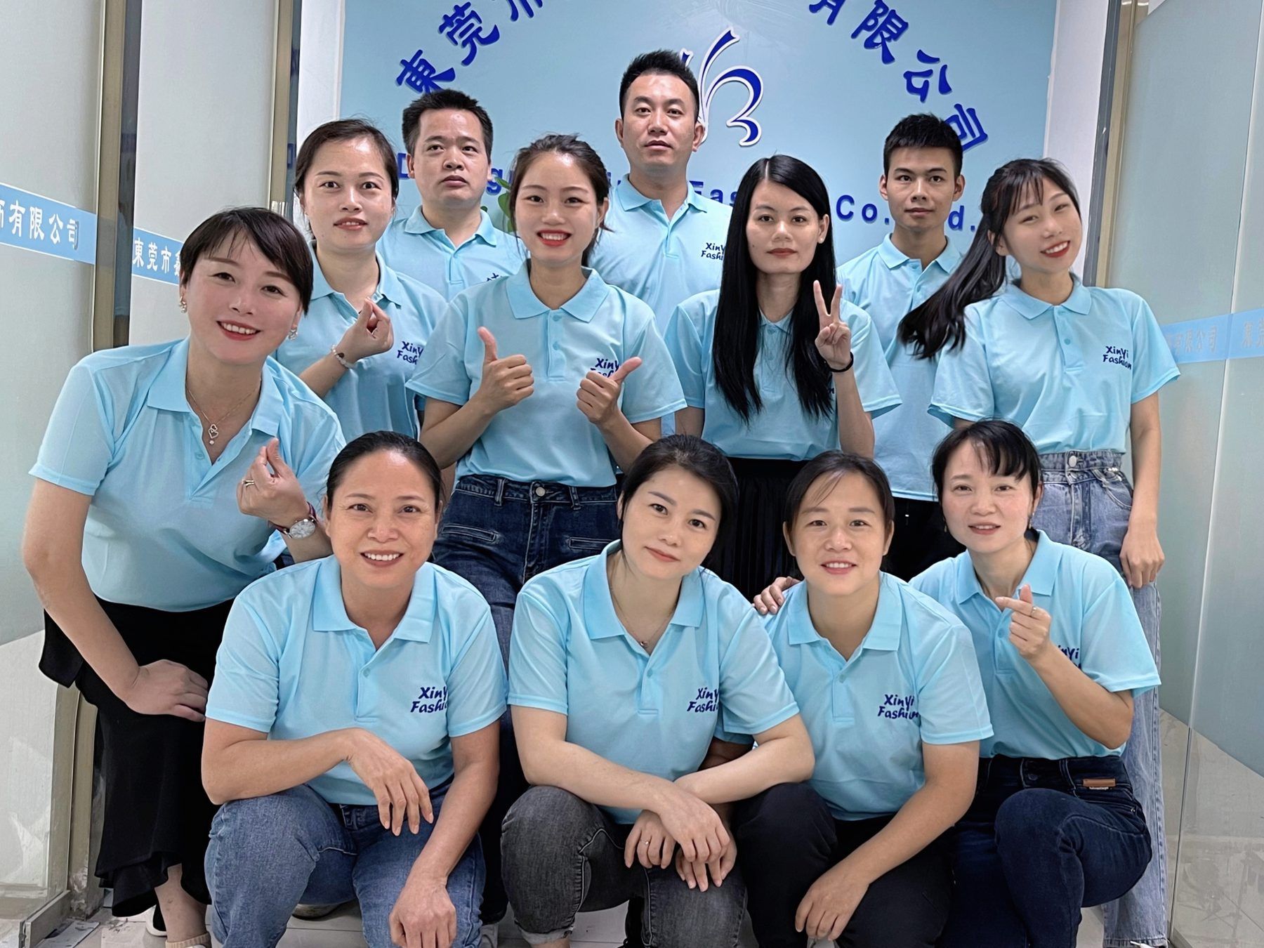 Company staff team in matching light-blue embroidered polo shirts and dark trousers at the office entrance