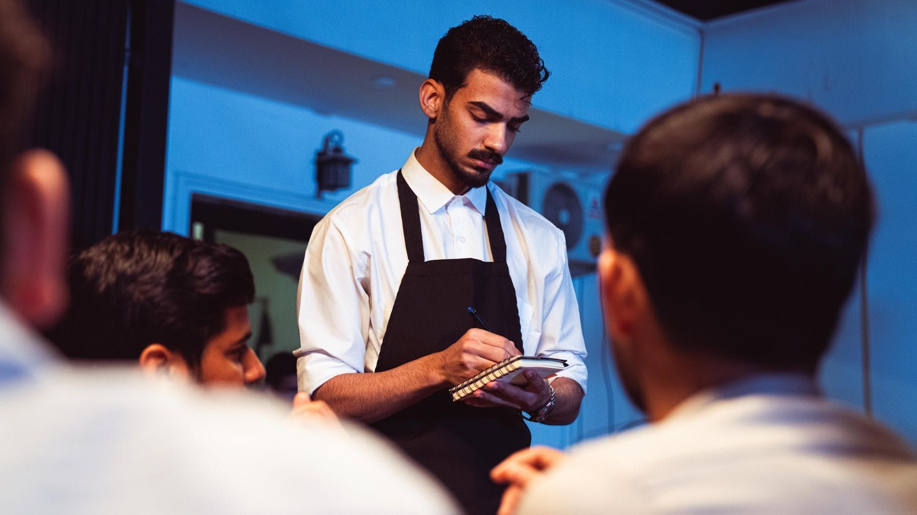 Waiters in black bar vests and white shirts carrying plates